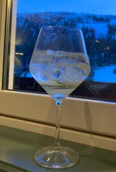 Glass of gin and tonic on window ledge in ski resort at evening
